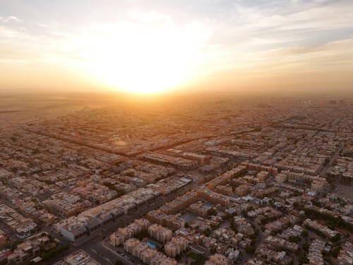 An aerial view of a city illuminated by sunlight with the sun setting on the horizon.