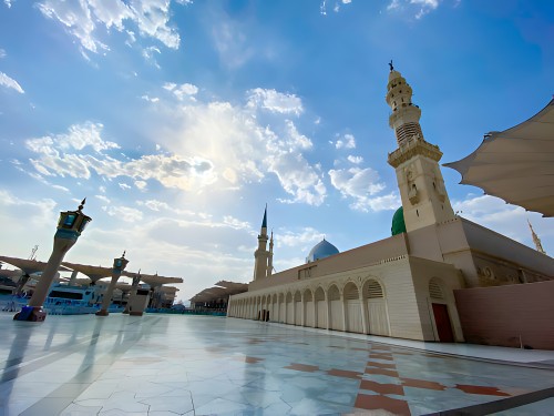 View of the courtyard of the Prophet's Mosque in Medina, showing the minarets and blue sky.