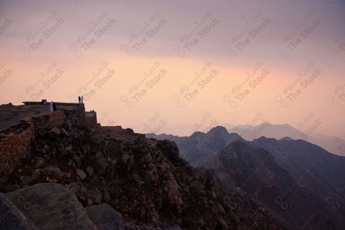 A shot of the rocky mountains in the city of Taif, and the sky appears cloudy in western Saudi Arabia, a group of people on top of the mountain.