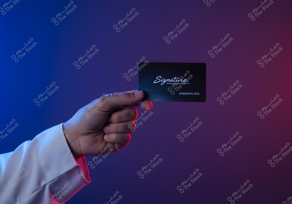 An image of a person\'s hand wearing a white shirt holding a black card with the word \"Signature\" written in white. The background transitions from blue to purple with red and blue lighting cast on the hand.