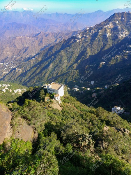 منظر لجبل السودة في منطقة عسير بالمملكة العربية السعودية. يظهر في الصورة التضاريس الجبلية مع الغطاء النباتي الأخضر المنتشر في المكان. هناك مبانٍ منتشرة على سفوح الجبال بعضها قريب وبعضها بعيد. في الأفق, تبدو مجموعة من الجبال الأخرى تحت سماء صافية.