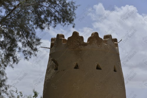 برج تراثي مبني من الطين يتوسطه مجموعة من الثقوب في حي طريف بالدرعية وتظهر السماء شبه صافية نهارًا