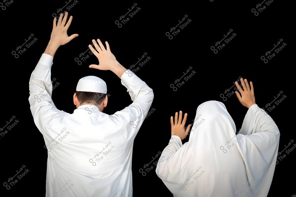 شخصان يرتديان ملابس إسلامية بيضاء ويرفعان أيديهما بالدعاء عند الكعبة.