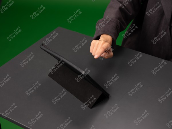 شخص يستخدم جهاز لوحي على طاولة سوداء.