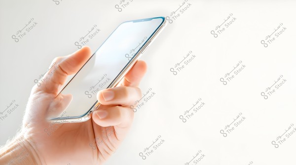 A hand holding a smartphone with a bright, shiny screen, against a completely white background highlighting the details of the mobile device.