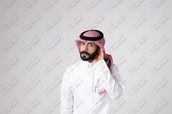 بورتريه رجل سعودي يقف على خلفية بيضاء ويشير بيده اتجاه معين