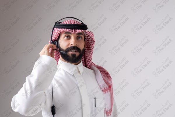 بورتريه رجل سعودي يلبس سماعة الرأس ويقوم بالتواصل عبر السماعة - خدمة العملاء ، مكالمة هاتفية