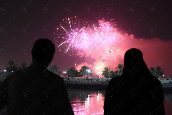 A man and a woman watching fireworks from events in the Eastern Province in Dammam, celebrations, fireworks.