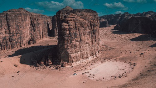 لقطة جوية لمحمية شرعان الطبيعية فيها سلسلة من الجبال في محافظة العلا، سماء ملبدة بالغيوم