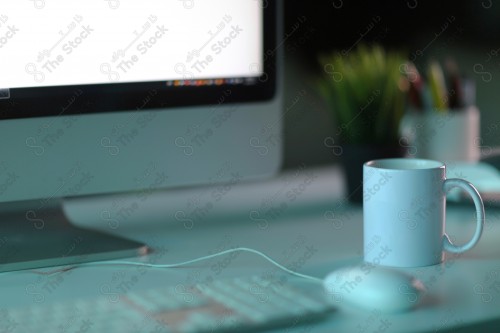 Close-up of a white table with a cup and a computer keyboard on it.