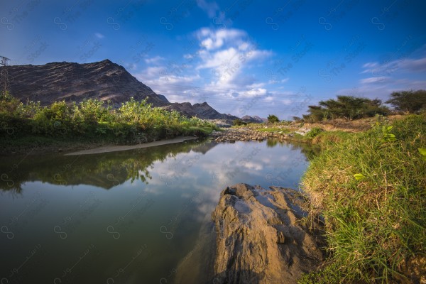 لقطة لبحيرة مائية في وسط الجبال في منطقة عسير ومن حولها سلسلة من الجبال الصخرية. اودية عسير، تجمع مياه