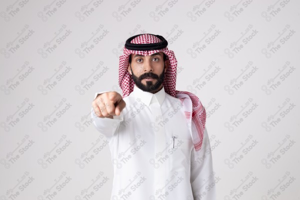 بورتريه رجل سعودي يقف على خلفية بيضاء ويشير بيده اتجاه معين