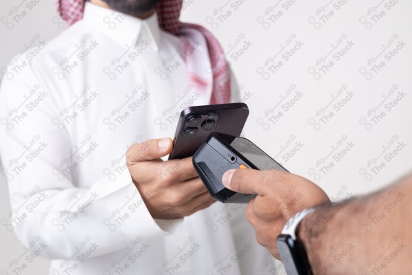 Portrait of a Saudi man holding a card and making automatic payments on a white background