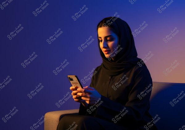 A photo of a woman sitting on a sofa holding a smartphone. The woman is wearing a black abaya and hijab, with a blue and purple backlighting that gives a modern and stylish feel to the image. The focus is on the woman and the phone.