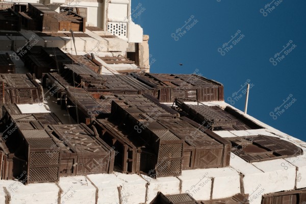 صورة لنافذة مشربية تقليدية مصنوعة من الخشب، على واجهة مبنى قديم تحت سماء زرقاء صافية.