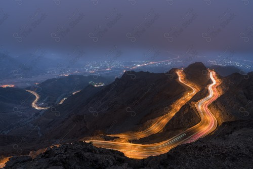 لقطة جوية لسلسلة من الجبال الهدا الصخرية في الطائف نهارًا، مجموعة من الطرقات وسط الجبال