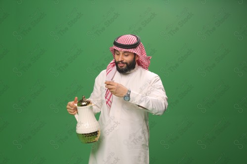 شاب سعودي على خلفية خضراء يرتدي الثوب و الشماغ، يقوم بعمل حركات بيده، يصب القهوه السعودية، احتفالات العيد