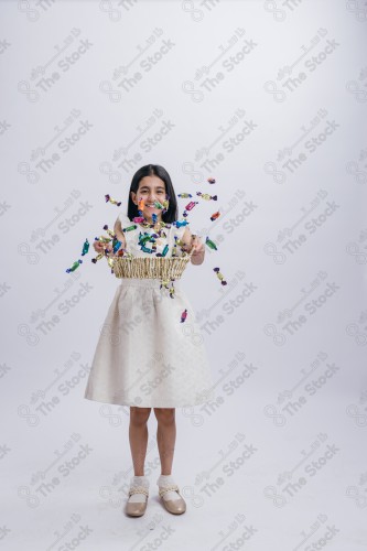 Portrait of a Saudi girl on a white background making gestures with her hands while smiling, souvenir photos, documenting a happy moment, Eid candy, Eid gifts, Eidiyat