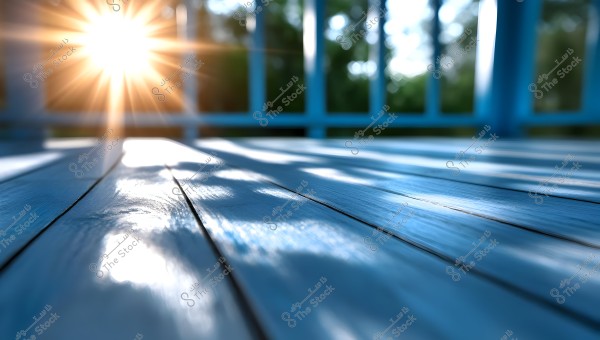 The image shows bright sunlight streaming through a blue wooden fence, casting long shadows on a blue wooden floor. The penetrating light creates beautiful shadow and shine effects on the surface.