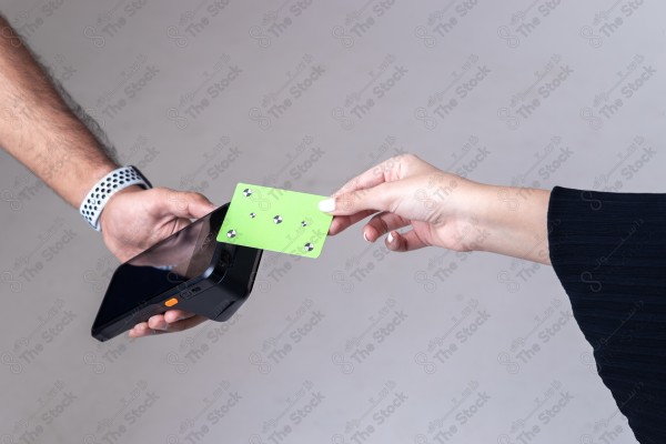 Portrait of a Saudi woman holding a card and making automatic payments on a white background