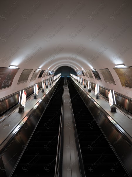 A long escalator in an underground metro station with soft lighting.