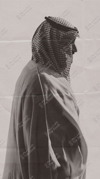 A portrait of a person wearing a thobe, ghutra, and agal, viewed from the side facing right. The background is simple and monochromatic, highlighting the traditional attire. The image may originate from Gulf countries.