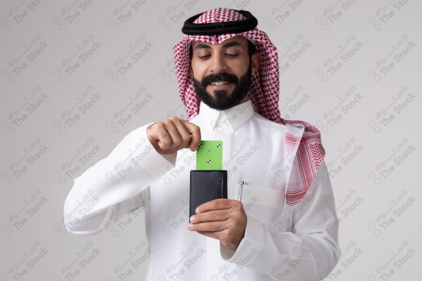 بورتريه رجل سعودي يحمل بطاقة خضراء على خلفية بيضاء