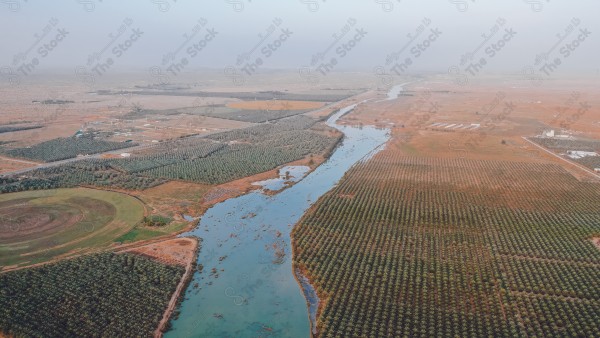 لقطة جوية لسلسلة من المسطحات الخضراء في وادي الرمة منطقة القصيم نهارًا، مجموعة من الأشجار في أحد الأودية, اودية واشجار.