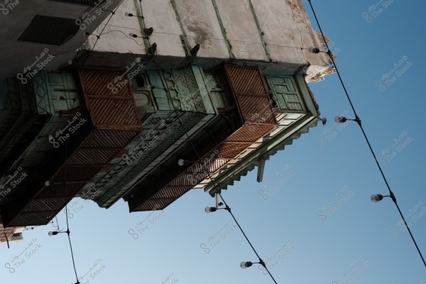 A section of an old traditional building with wooden latticework in the historic city under a clear blue sky, with hanging lights in the foreground.