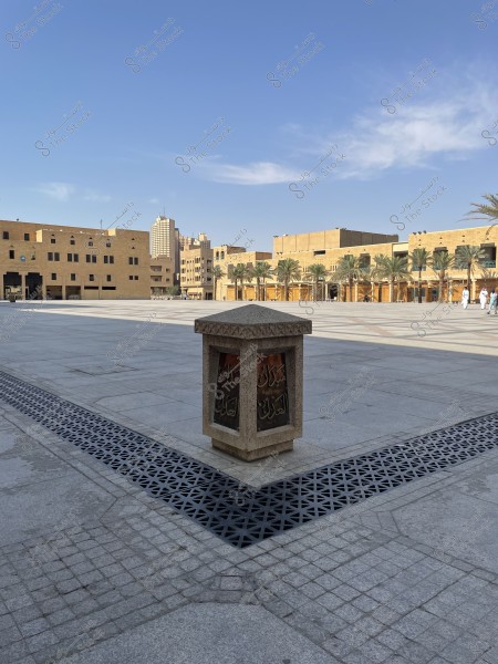 The picture shows a wide courtyard with a small architectural element in the foreground that says “The Field of Justice”. In the background, there are modern buildings in line with the traditional architectural style and surrounded by palms. The sky is blue and studded with some white clouds.