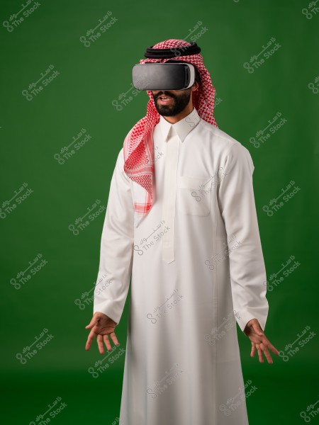 رجل يرتدي الثوب السعودي والنظارات الافتراضية, يقف أمام خلفية خضراء.