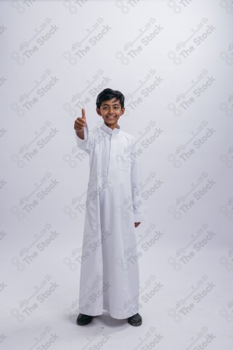 Portrait of a Saudi child on a white background making gestures with his hands while smiling, souvenir photos, ، documenting a happy moment, Eid candy, Eid gifts, Eidiyat, incense