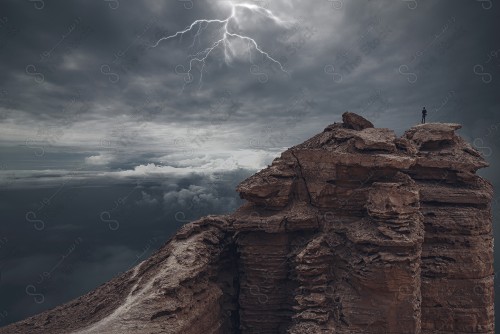 Aerial shot of a tourist standing on one of the Tuwaiq Mountains called the Edge of the World in a rainy time, a chain of rocky mountains in Riyadh.