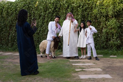 A Saudi family gathered in the eid , the eid sheep, the sacrifice, aodhiyah, the eid , visits and the family gathering, the customs of the eid in the Saudi society, a happy family atmosphere, eid and occasions.