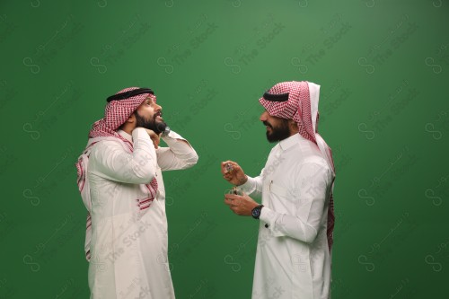 رجل سعودي يرتدي الزي السعودي التقليدي يطيب ضيفه بالدهن عود في أحد المناسبات