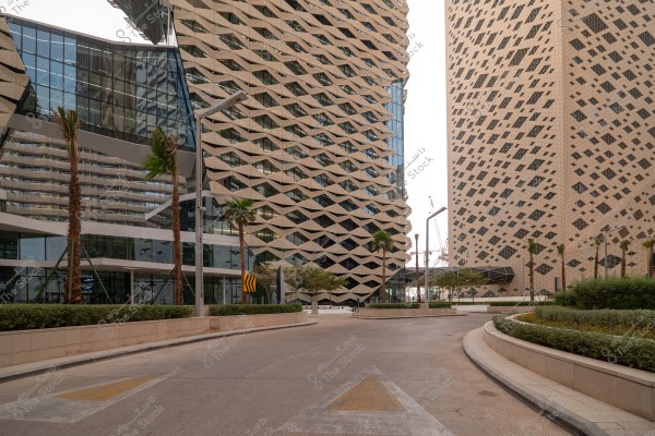 An image of modern buildings with contemporary design in an urban setting featuring skyscrapers with geometric patterns and glass panels. The road in the foreground is lined with palm trees and well-maintained gardens, adding a touch of nature to the sleek urban landscape.\r\n\r\n###