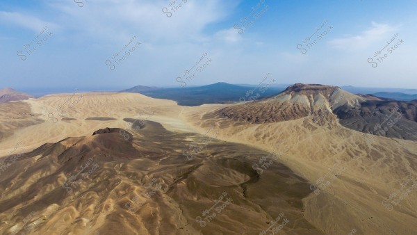صورة جوية لمنظر طبيعي صحراوي يظهر الجبل الابيض في حرة خيبر . تتضمن الصورة العديد من الجبال والتلال و فوهات البراكين ذات الألوان الرملية والبنية, ويبدو أن هناك سماء زرقاء صافية في الخلفية, مع بعض السحب الخفيفة.