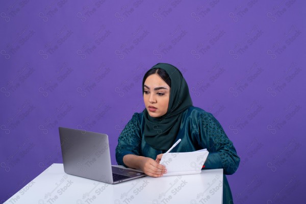 Portrait of a young Saudi woman wearing an abaya and hijab, holding a pen and thinking, against a purple background