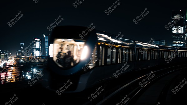 قطار مترو يسير بسرعة في مدينة مضاءة ليلاً, مع أفق يحتوي على مبانٍ شاهقة الأضواء.