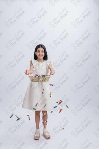 Portrait of a Saudi girl on a white background making gestures with her hands while smiling, souvenir photos, documenting a happy moment, Eid candy, Eid gifts, Eidiyat