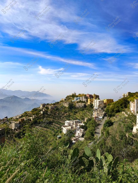 A scenic view of a green mountainous area with houses built on terraced slopes. In the foreground, there are trees and shrubs, while misty mountains can be seen in the background. The sky is clear blue with some white clouds.