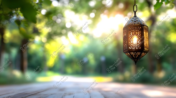 مصباح معدني مزخرف معلق في الهواء في حديقة خلابة, مع خلفية ضبابية تبرز فيها الأشجار وأوراق الشجر الخضراء تحت ضوء الشمس الدافئ. الضوء الخافت من المصباح يضفي جواً هادئاً وتراثياً على المشهد الطبيعي.