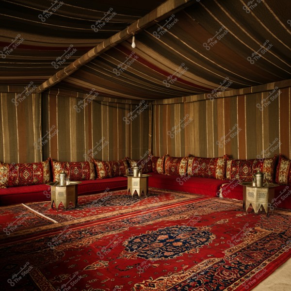 A traditional Arabic tent decorated with warm and vibrant colors. The tent features a long cushioned seating with ornate red and gold-patterned backrests, and the floor is adorned with oriental carpets. Small decorative metal tables are placed in the center, adding a traditional and elegant touch to the setting.