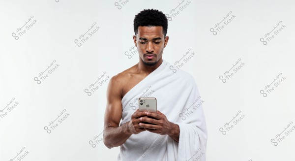A portrait of a man wearing a traditional white garment, likely traditional in parts of the Middle East or Africa, holding a smartphone in his hands. The background is white, enhancing the focus on the person in the image.