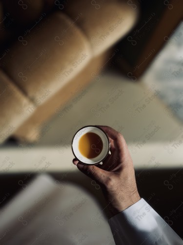 Close-up of a man holding a cup full of Saudi coffee in hand.