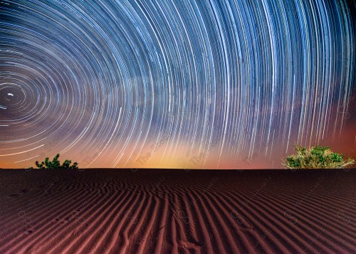 A shot showing stars and meteors in a circular manner over the sand dunes in one of the Saudi deserts.