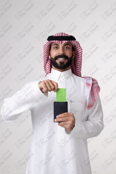 بورتريه رجل سعودي يحمل بطاقة خضراء على خلفية بيضاء