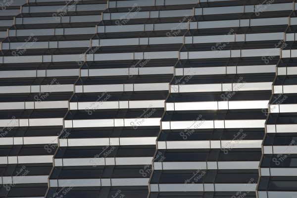 An image showing the facade of a building with a repetitive pattern of rectangular glass windows set at tilted angles. The windows interlock creating a 3D effect, with light reflections on the glass enhancing the architectural geometric details.