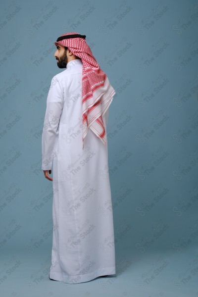 Portrait of a Saudi young man wearing the Saudi dress, and happiness and joy appearing on his features, against a heavenly background