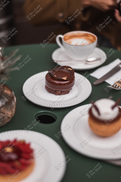 حلوى بالشوكولاتة على طبق أبيض بجانب فنجان قهوة على طاولة خضراء.